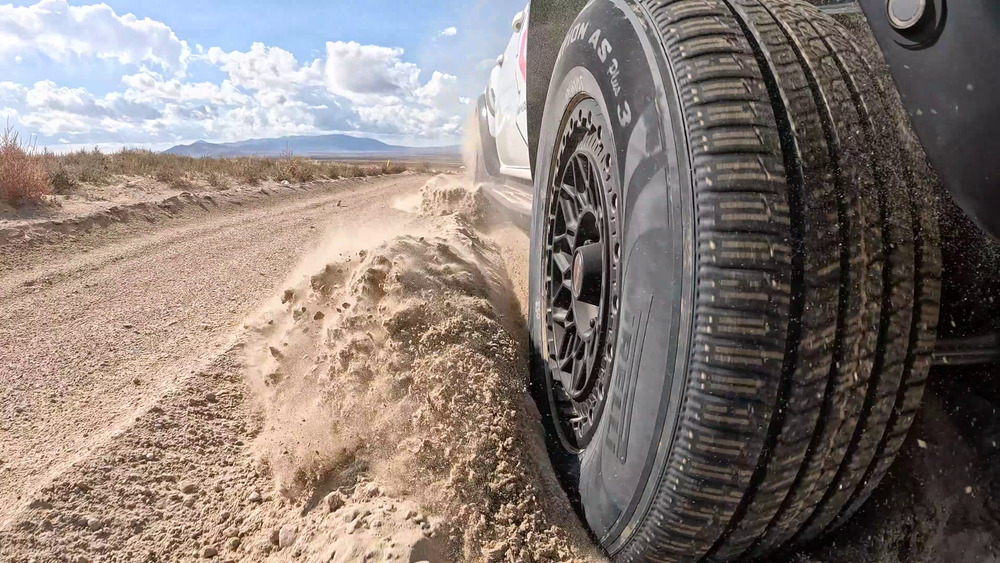Pirelli Scorpion AS Plus 3 wirft neben einem Ford Ranger Raptor losen Sand auf